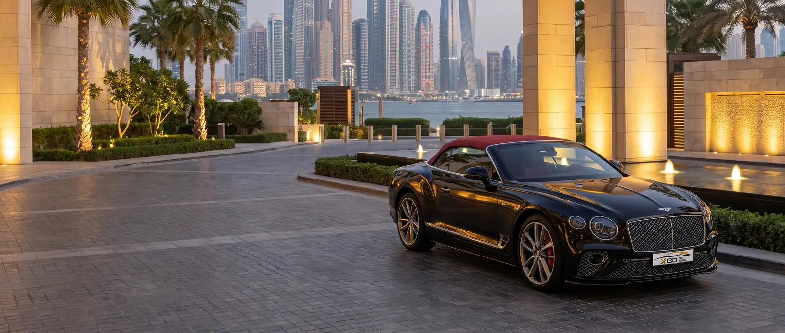 Bentley convertible from XGO Car Rental at a Palm Jumeirah hotel entrance at dusk